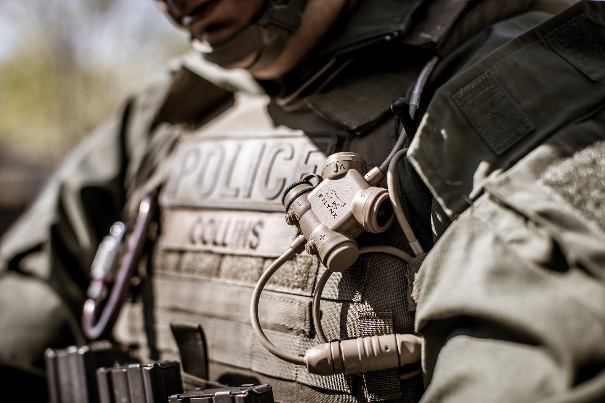 Person in tactical gear with 'POLICE' and 'COLLINS' visible with silynx clarus I on a blurred background