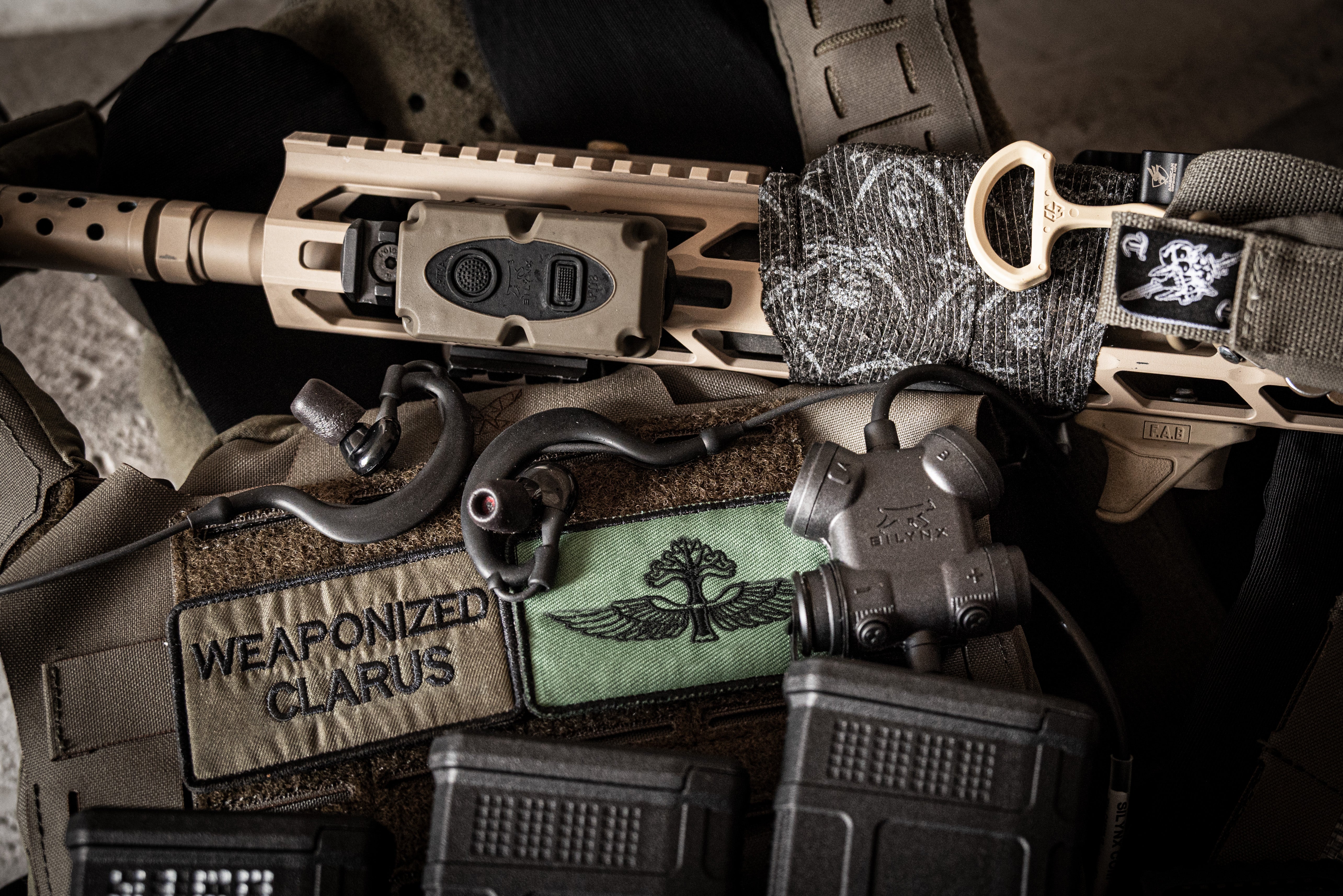 Close-up of SILYNX Clarus 1 and tactical gear with 'Weaponized Clarus' patch on a dark background