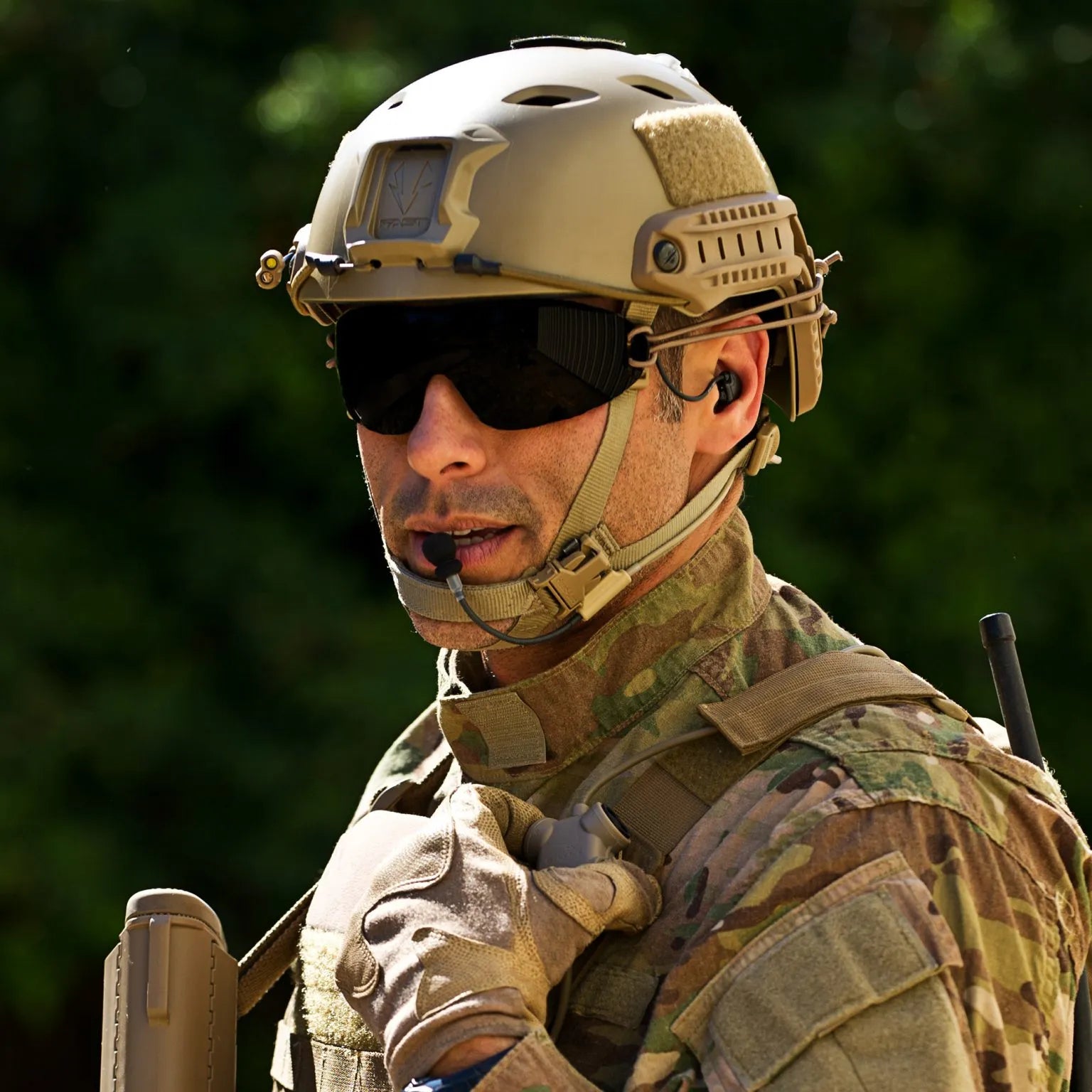 Soldier with helmet and sunglasses wearing Silynx Boom Microphone, earpiece and Clarus control box.