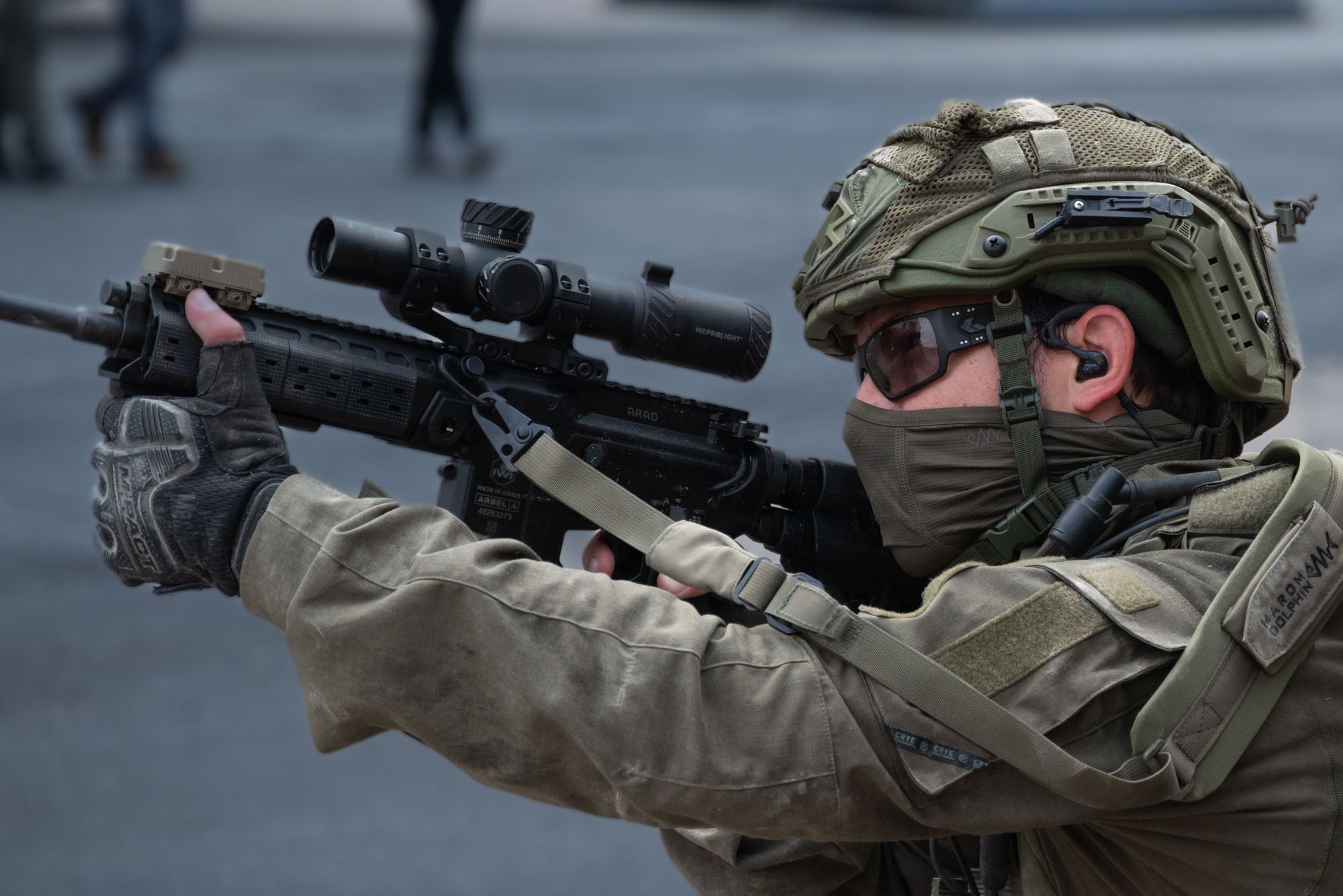 Soldier in military gear holding a rifle with a scope With Silynx Earpiece and Wireless PTT on a blurred background