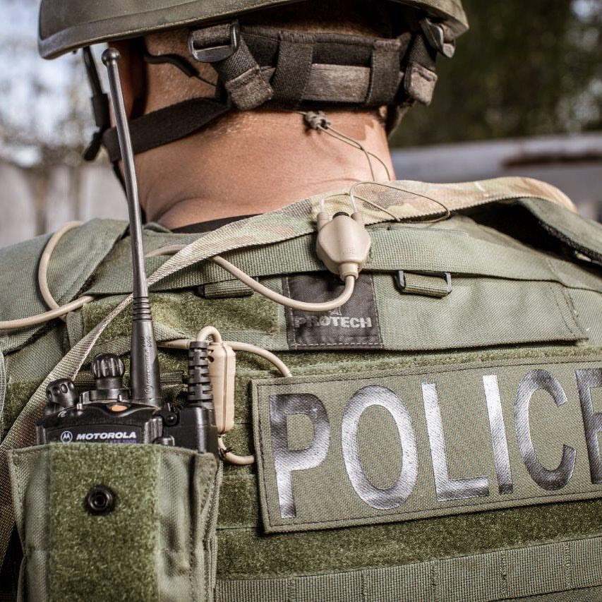Soldier wearing a tactical vest with 'POLICE' on it, equipped with  Silynx communication devices.