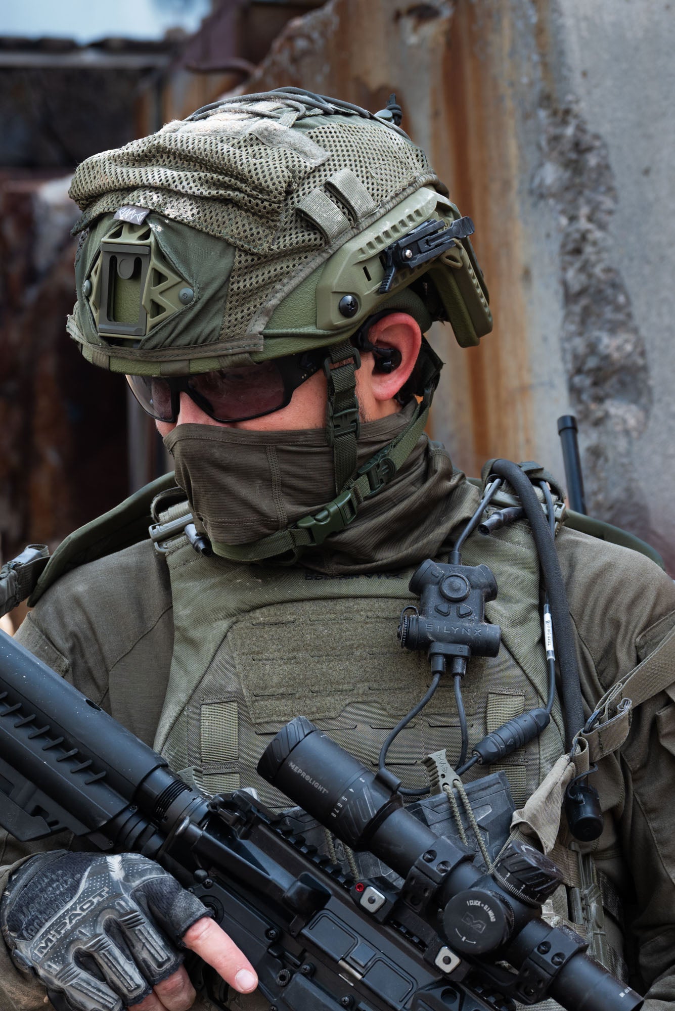 Soldier in tactical gear holding a rifle with Silynx Clarus II,  a helmet and face mask in an urban setting