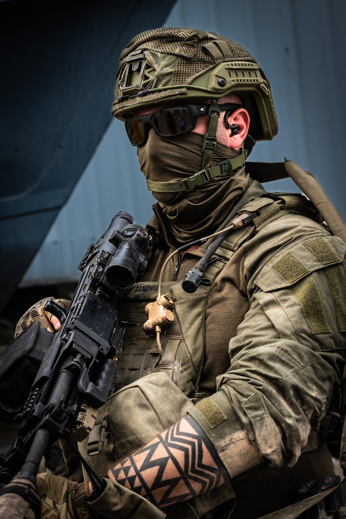 Person in military gear with silynx clarus I, tactical rifle and helmet, sitting against a dark background