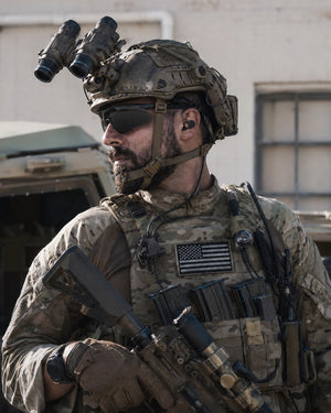 Soldier in camouflage gear with tactical equipmentת Silynx custom earmolds and Clarus control box. Outdoor setting