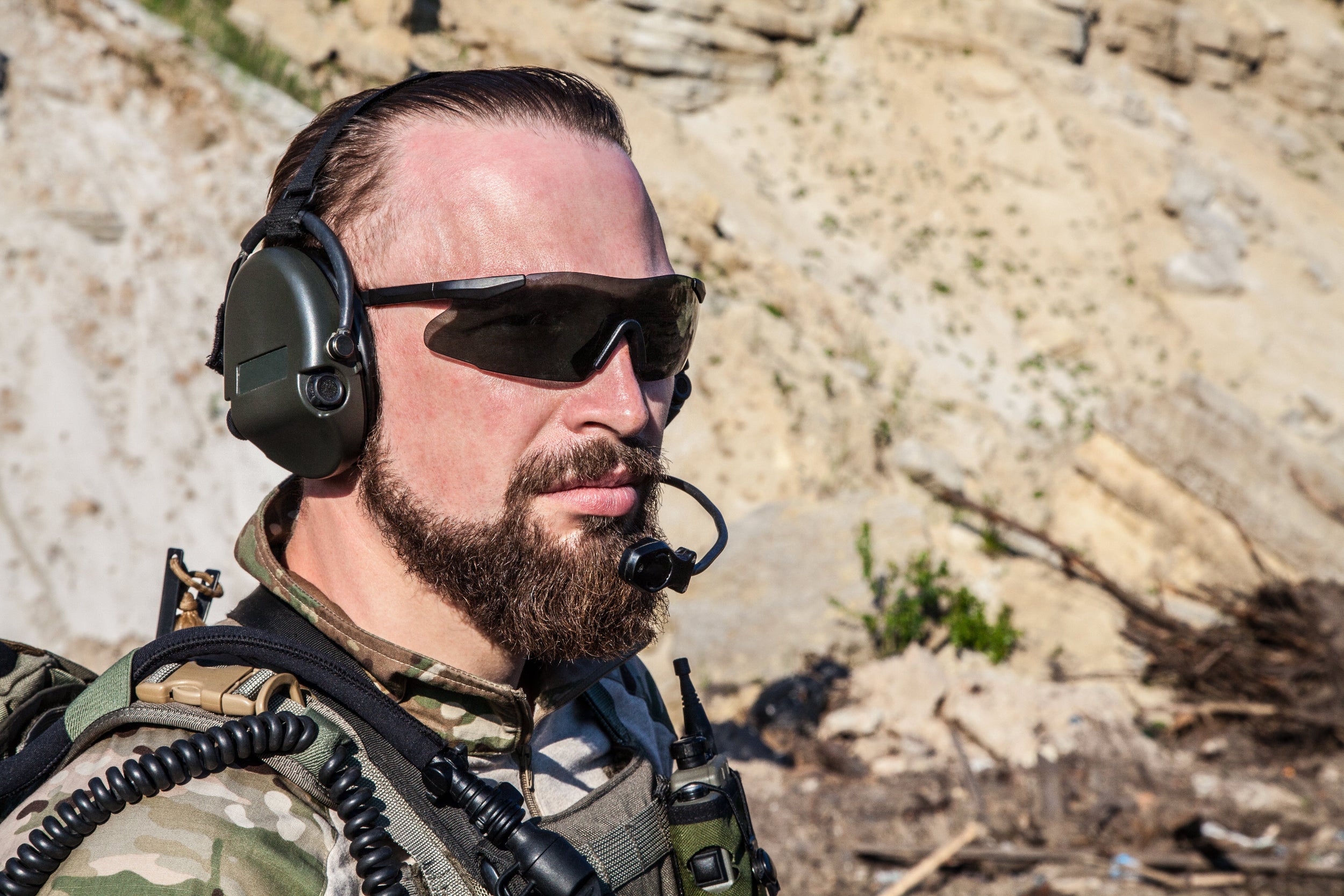 Soldier in tactical gear with Silynx Protego SDR communication equipment in a rocky outdoor setting