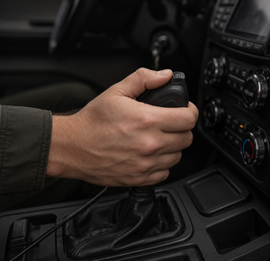 Hand operating SIlynx FInger PTT on a car gear shift lever inside a vehicle.